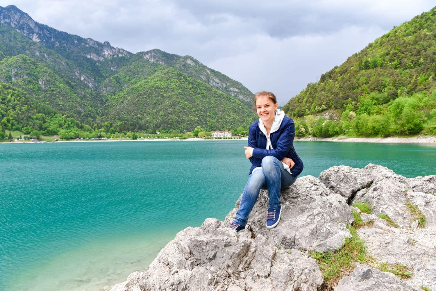 A woman sitting on a rock by a body of water.
