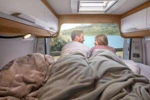 Gemütliches Camper-Bett mit Blick auf See, ideal für Abenteuer und Naturerlebnis.