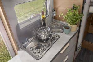 Küchenzeile im Moon Camper mit Herd, Topf und Kräutertopf, perfekte Kocherfahrung unterwegs.
