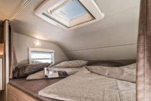 Geräumiges Bett im Moon Camper mit Dachfenster und natürlichem Licht.