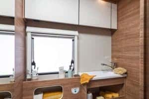 Hell erleuchteter Waschtisch mit Holzoptik im Moon Camper, praktische Stauraumlösungen integriert.