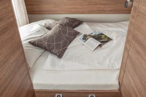 Gemütliches Schlafbereich im Moon Camper, hochwertiges Bett mit Kissen und Aufbewahrung.