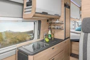 Modernes Wohnmobil-Kücheninterieur mit Holzoptik und Stauraum.