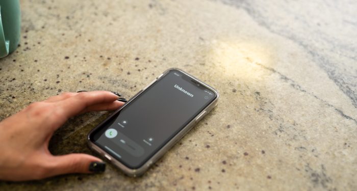 Fraud or fraudulent schemes. Close-up of a woman's hand holding a phone with an unexpected incoming call from an unknown person