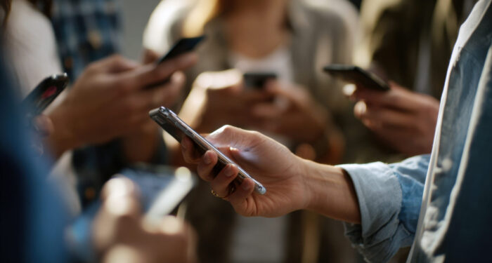 Close-up of multiple people's hands holding and interacting with smartphones, illustrating digital communication, social media, and technology use in a group setting.