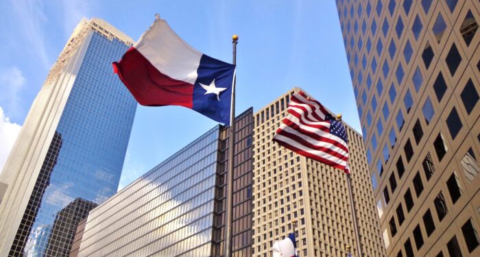 Low angle view of United States of America flag and Texas state flag in front of modern skyscrapers in downtown Houston (skyline / skyscrapers) on a summer day - Houston, Texas, USA