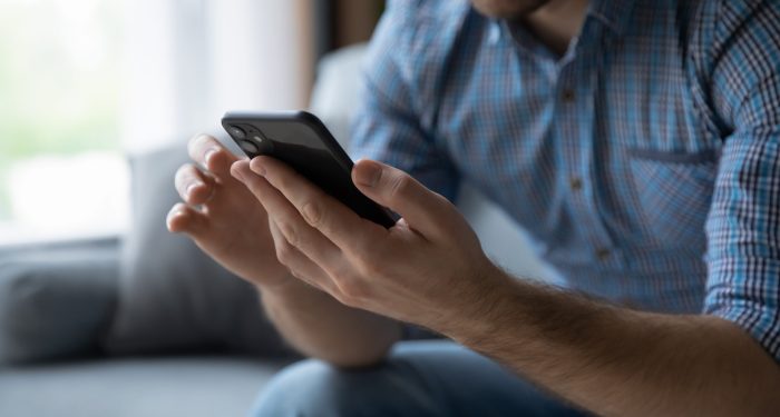Close-up of a man reading a text message on his smartphone, representing the text marketing practices at issue in the TCPA's do-not-call rules