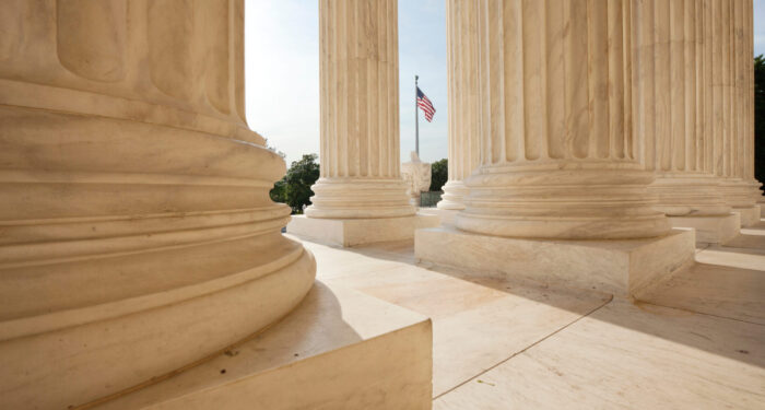 An American flag viewed between pillars of Supreme Court building in Washington DC