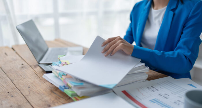 woman plans a finance and budget audit by reviewing organizing office financial documents.