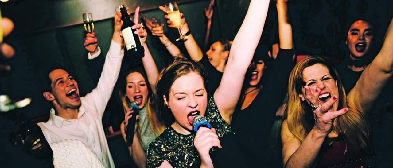 Groep jongeren die uitbundig meezingen op karaoke tijdens een fuif.