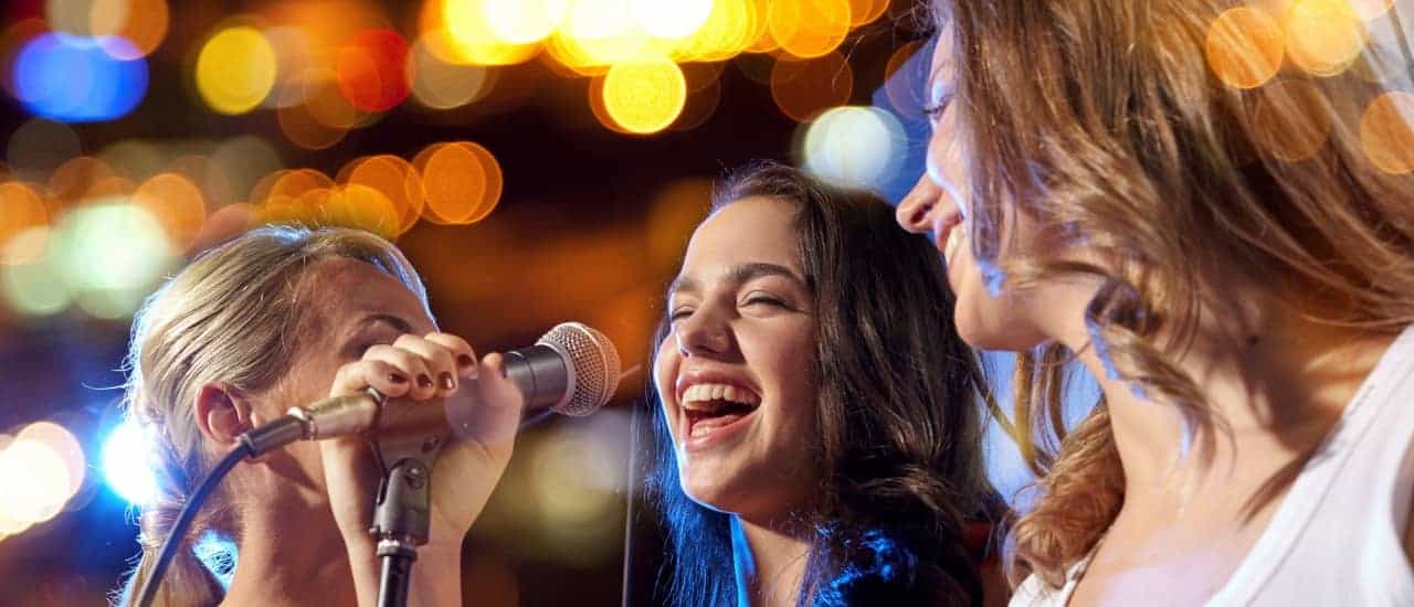 Groep vrouwen zingen tijdens een karaokefeest.