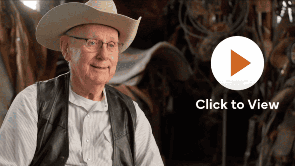 Smiling man with cowboy hat in a saddle room setting, wearing a brown vest, with a 'Click to View' play button overlay.