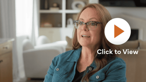 Woman in teal jacket in a living room setting, with a 'Click to View' play button overlay