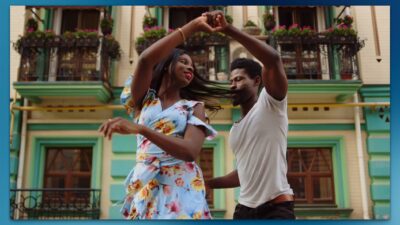 Pareja bailando merengue alegremente en una calle colorida.