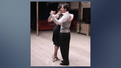 Pareja bailando tango, abrazados y con elegante vestimenta.