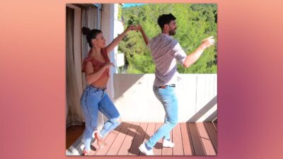 Pareja bailando salsa en una terraza soleada.