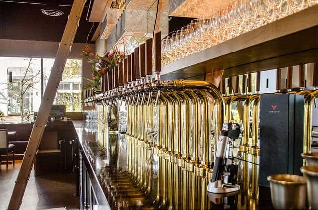 A row of wine-on-tap dispensers stretches far behind a wood bar.