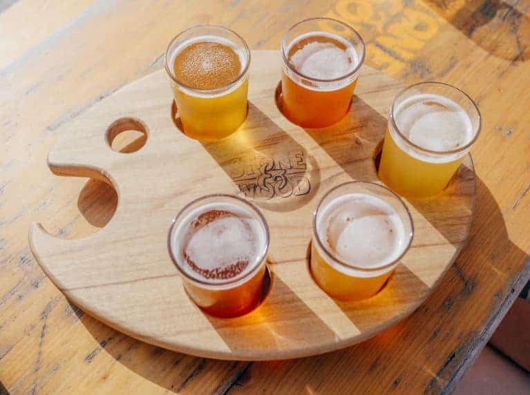 A beer flight made up of 5 mini pints of amber colored beer. Brewery events like flight beer tastings allow patrons to sample all your most popular beers.