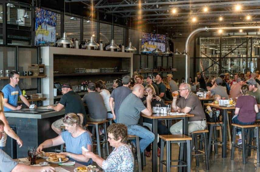 A brewery taptoom full of patrons eating, drinking, and enjoying conversation. Hosting special brewery events can help full up your brewery with excited patrons.