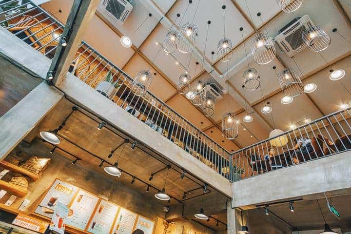 For a dining room with a high ceiling, light fixtures are crucial; hanging pendant lights light up the space and give this restaurant with a dine-in balcony a modern look 