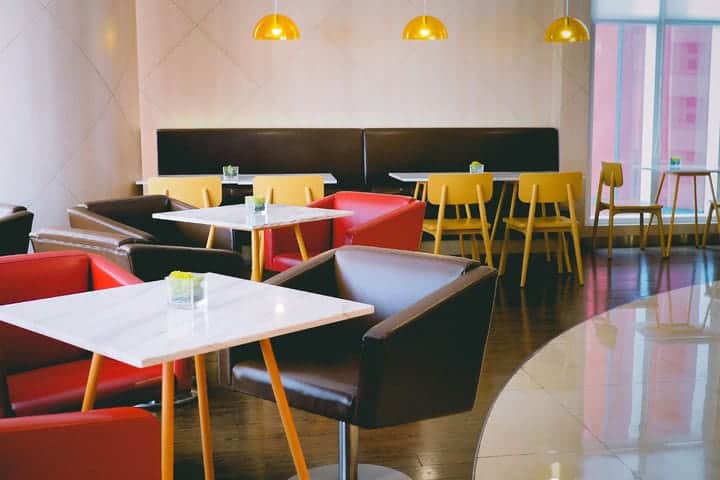 Modern restaurant interior design may feature solid colors like black and red leather chairs, yellow accents and marble table tops with clean lines and simple lighting