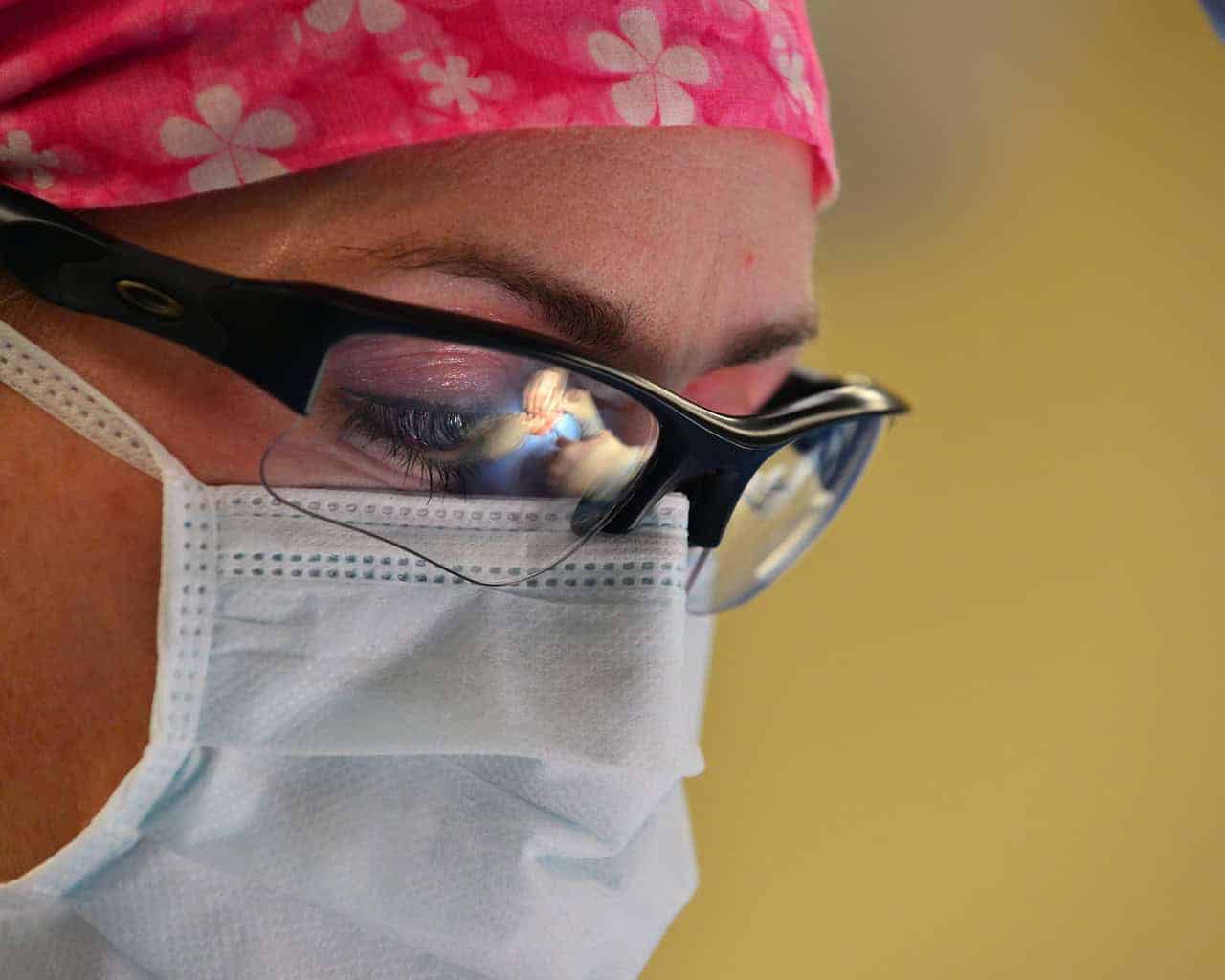 A close-up of a woman wearing a face mask and safety glasses. Face masks help contain bacteria and prevent the spread of illness throughout your nursing facility