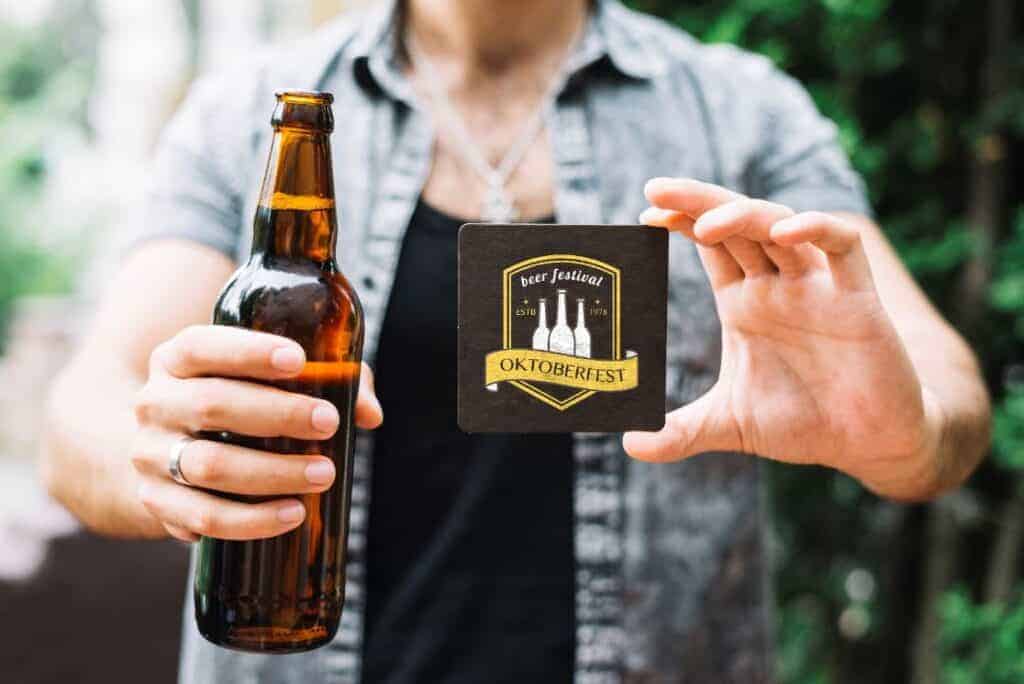 This man is holding a custom branded beer bottle and coaster - two examples of brewery branding that can promote your business