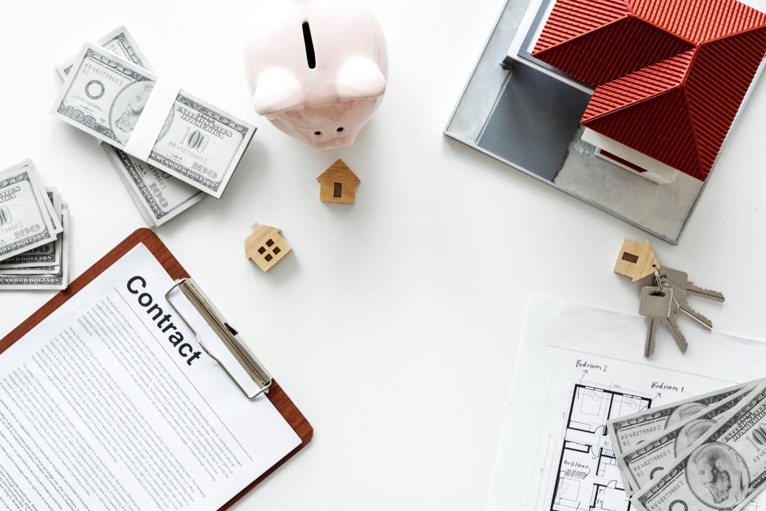 A rental contract sits on a table with keys, a small house, a piggy bank, and cash. A great way to avoid property damage to your rental units is to ensure terms are clear in your rental contract