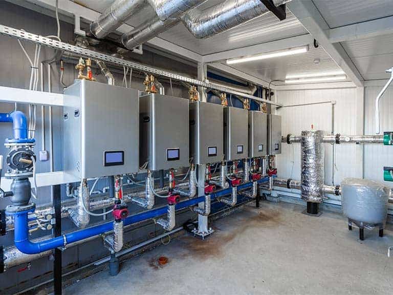Several gas boilers are installed in an equipment room of a commercial building.