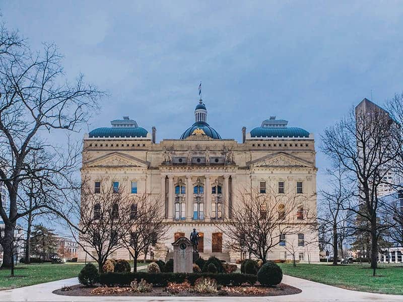 The Indianapolis capitol building sits between several trees in Indiana.