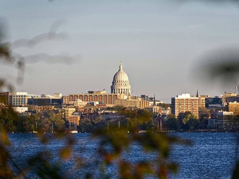 The Wisconsin State Capitol rises over the Madison skyline and Lake Mendota.
