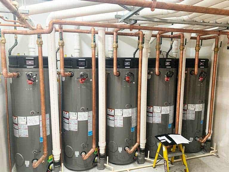 Five high efficiency water heaters are installed against the wall in a commercial building.