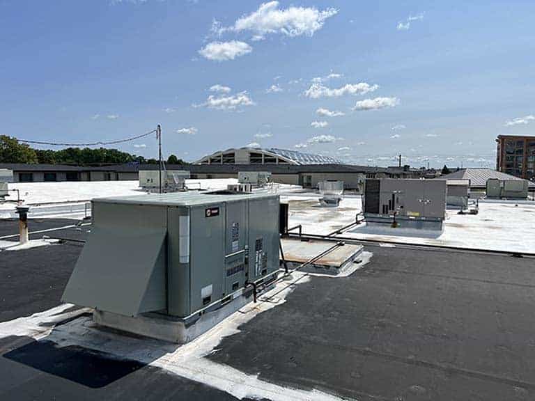 A large rooftop unit sits atop a building under a clear blue sky.