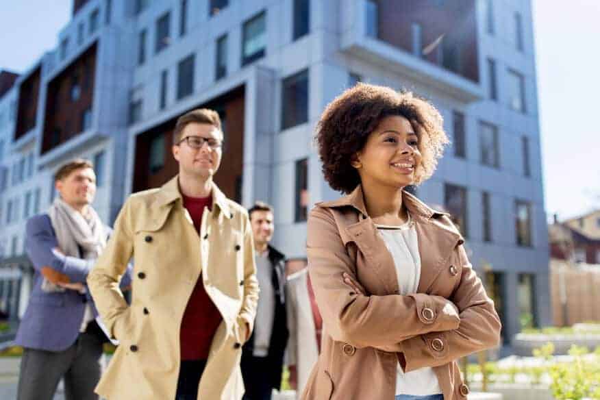 A group of young adults walking in front of an apartment building.