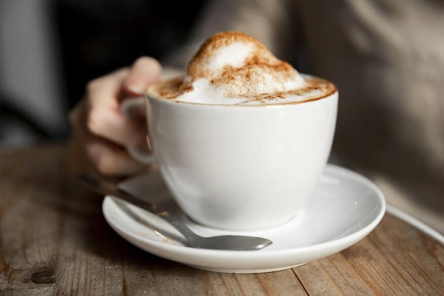 A close-up of a cup of foamy cappuccino coffee sprinkled with cinnamon, made better tasting because of the benefits of soft water.
