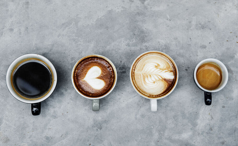 An overhead view of four different mugs filled with different coffee drinks, like a latte with a foam heart and creamy espresso. Every one of these coffee types is affected negatively by your hotel's water quality. 