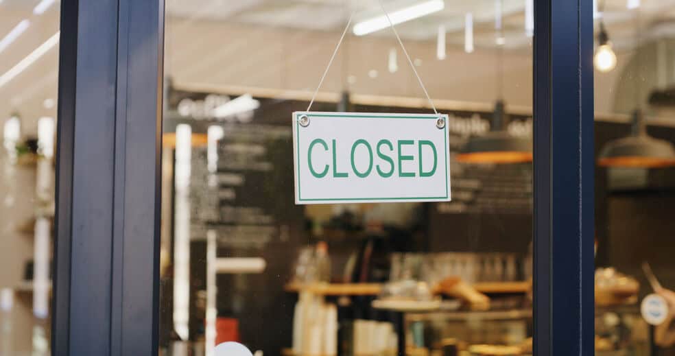 A "closed" sign hangs in the door of an empty restaurant, which was forced to shut down because it did not have a water heater redundancy.