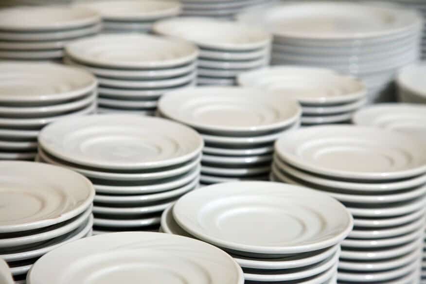 Rows of clean, white, restaurant coffee cup saucers in stacks are usable because of a water heater redundancy.