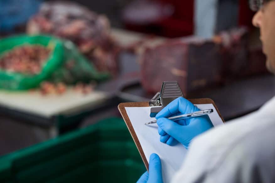 Partial picture of a man in a white coat making notes about health code violations on a clipboard, because there was no water heater redundancy.
