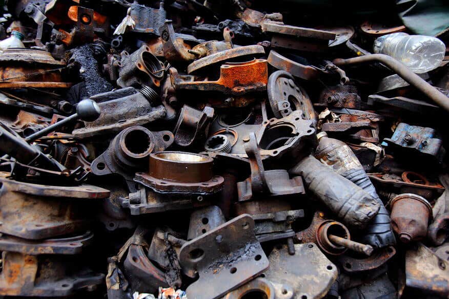 Rusty and old machine parts, some of them from discarded old commercial water heaters, are piled up in a junkyard. 