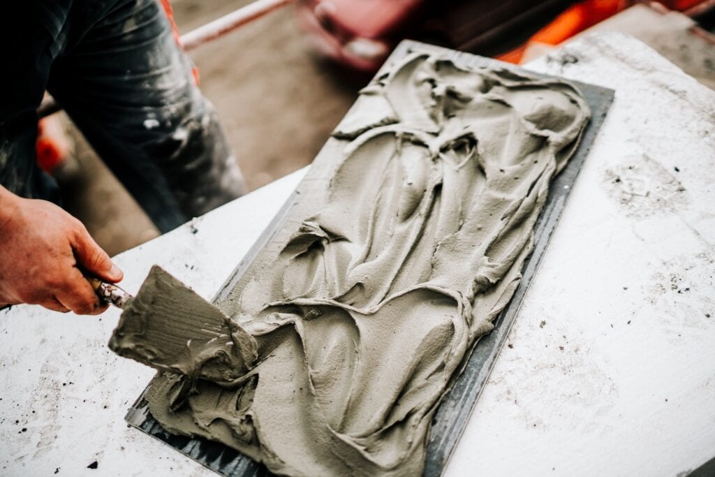 Industrial worker hands working on construction site and placing stone tiles on facade