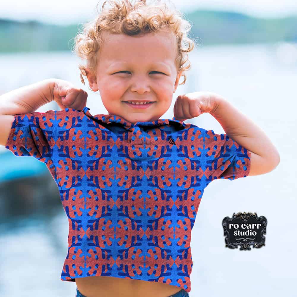 LIttle boy wearing shirt printed with Belle Batik fishbones in red and blue.