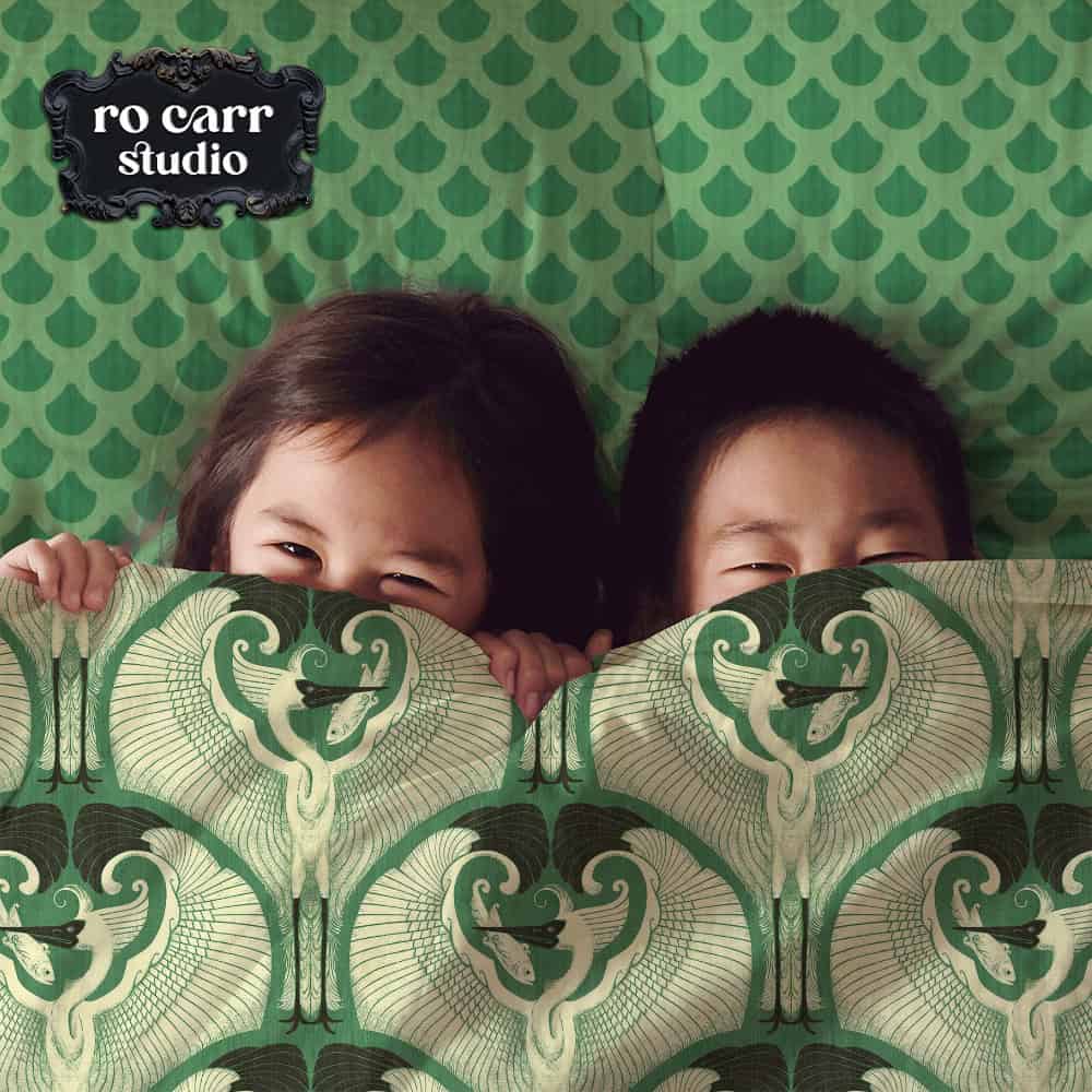 Bedding mockup of two cute kids under the covers printed with the great egret pattern.