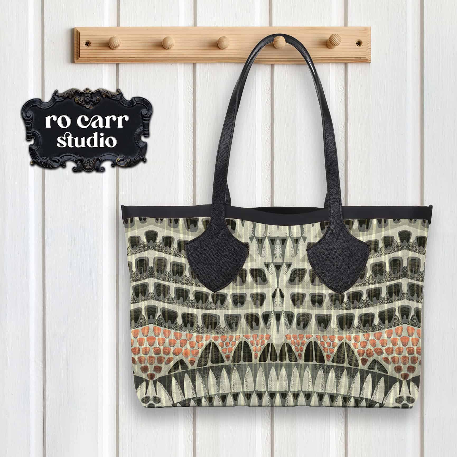 Leather and fabric tote bag hanging from a peg, printed with the Armadillo pattern.