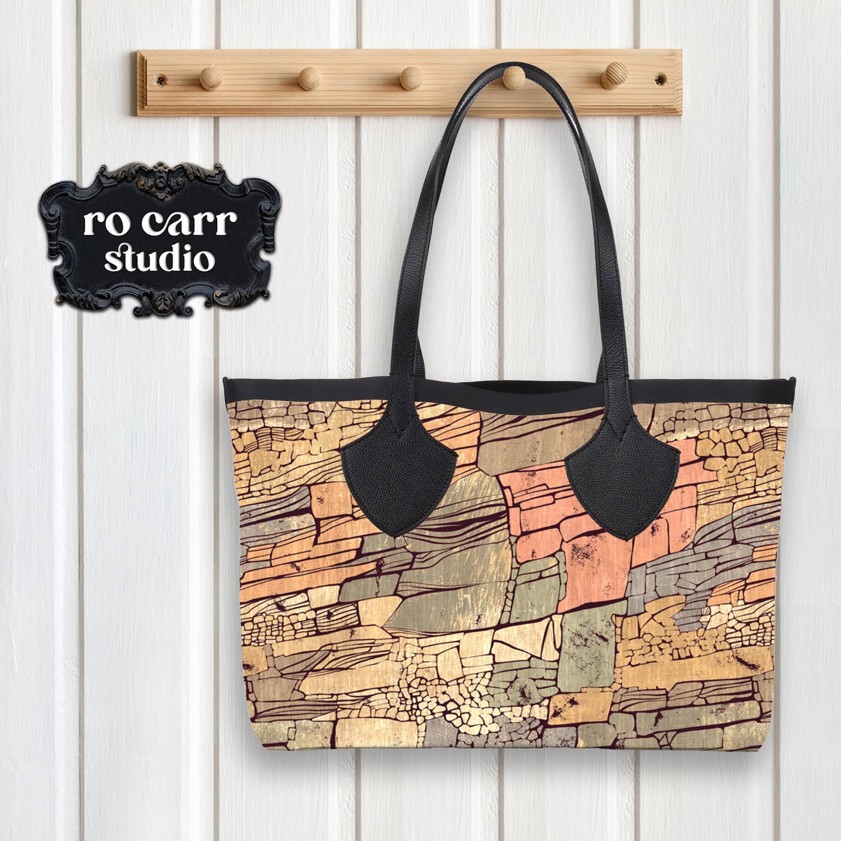 Tote bag with black leather handles and trim hanging on a peg, printed with the Rock Candy Mountain pattern.