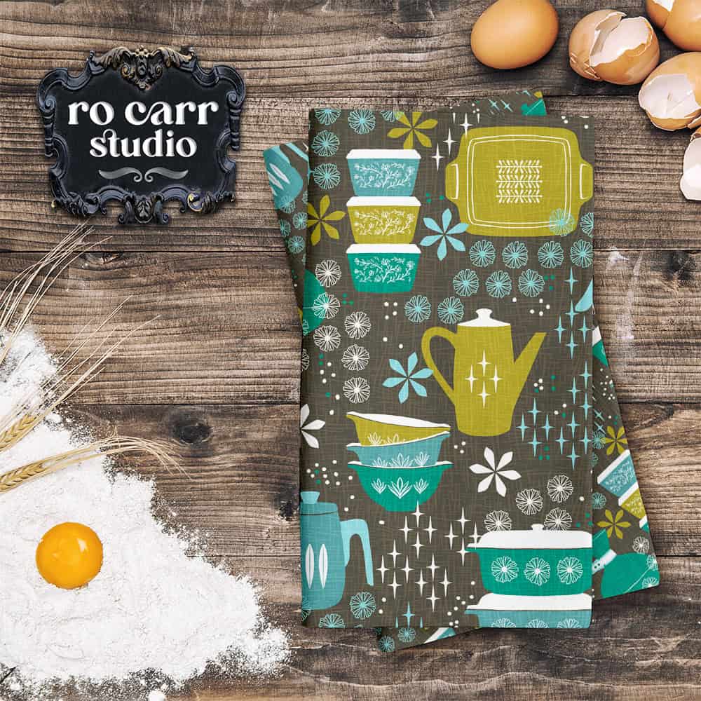 Kitchen counter with eggs and flour, and a a stack of kitchen printed towels showing the Hostess with the Mostest pattern in teal.