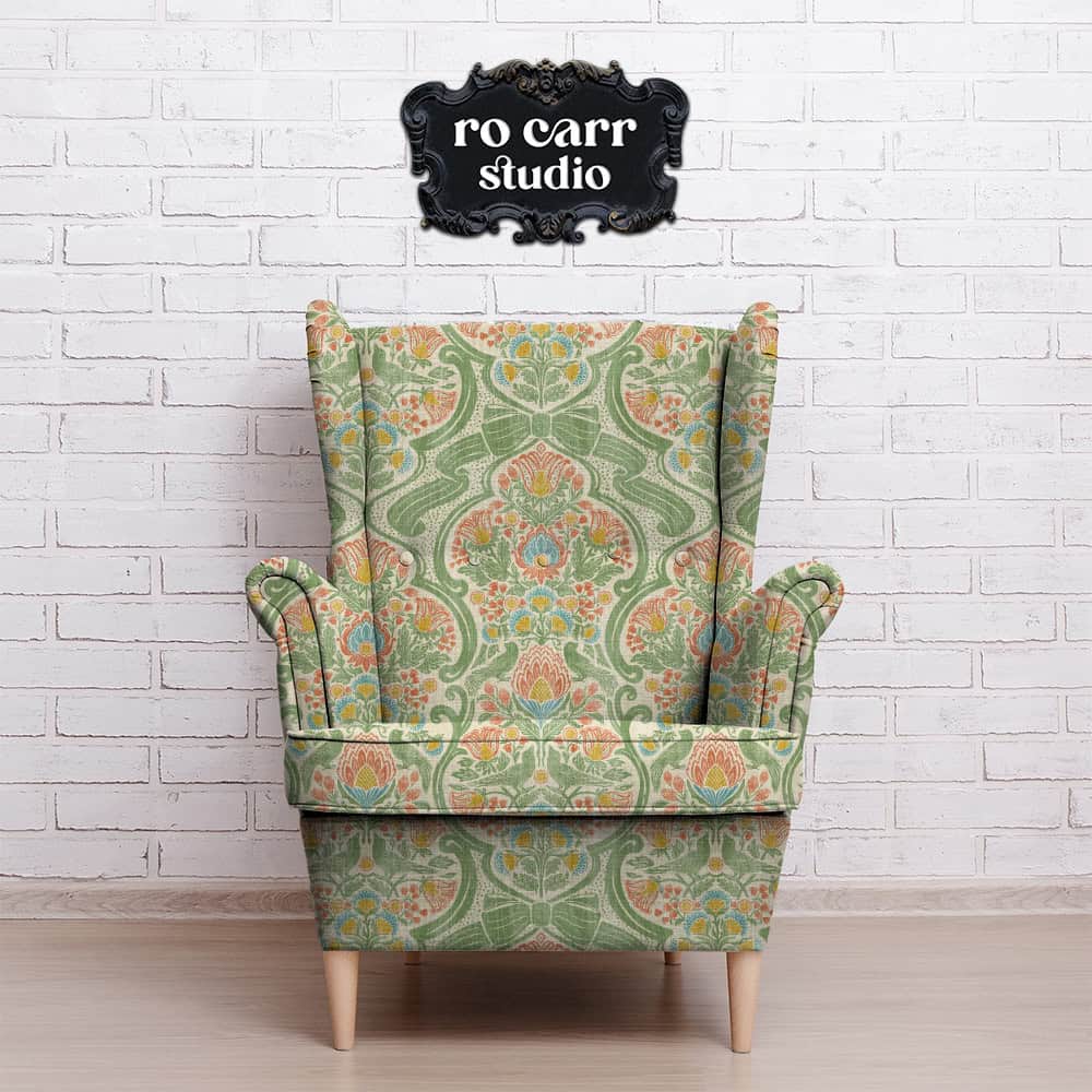 Wingback armchair upholstered in a botanical chintz print, shown against a white brick wall.