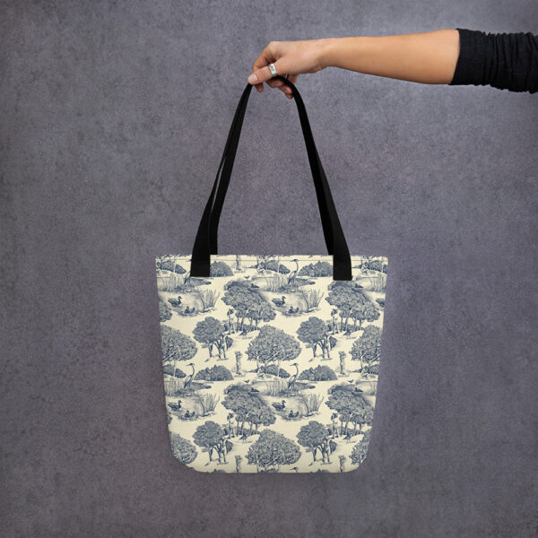 Tote bag printed with birds & birders toile de juoy, hanging from hand.