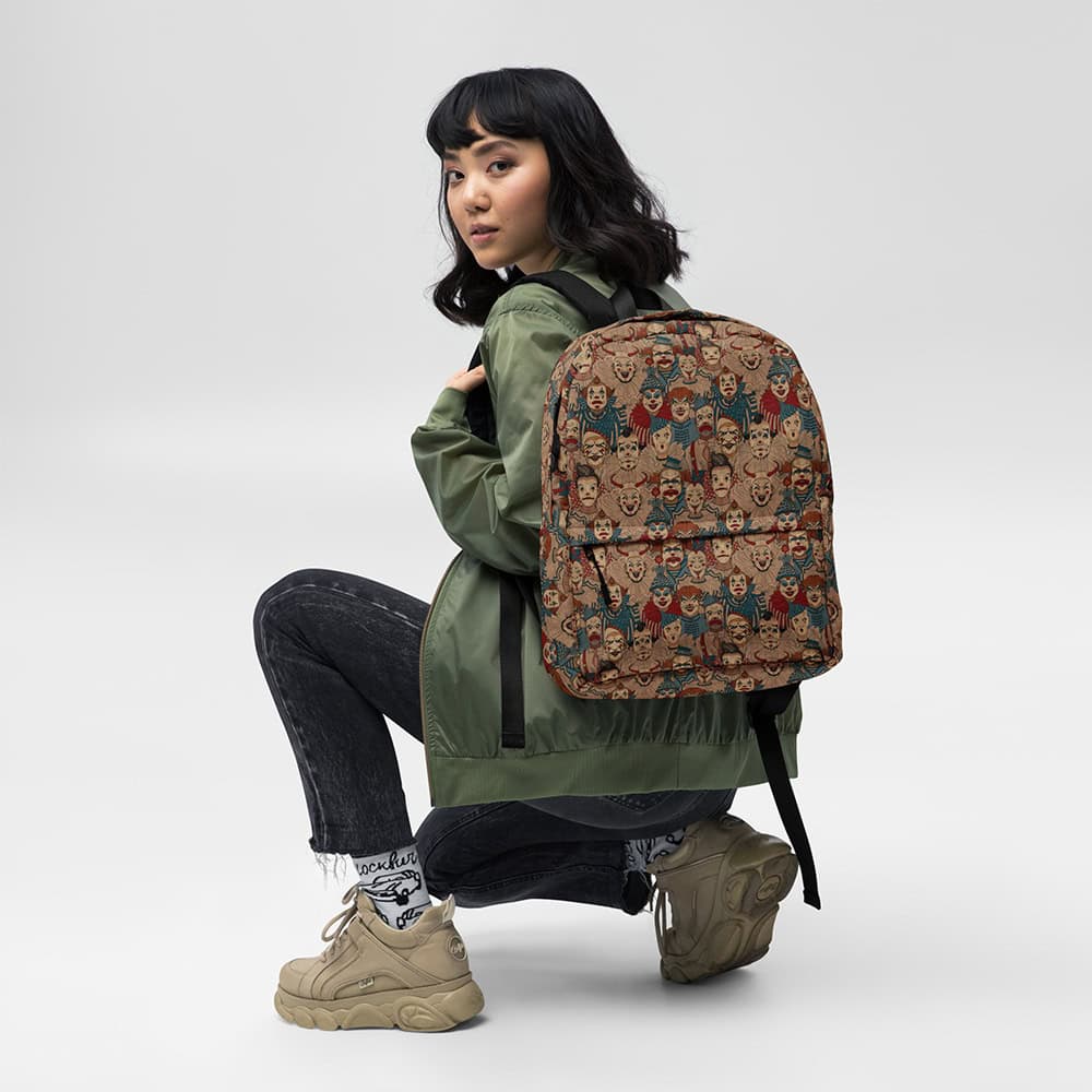Woman crouching wearing Creepy Circus Backpack over a green jacket, front pocket print visible.