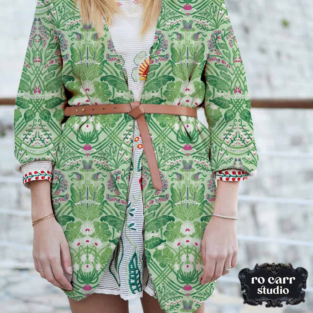 Woman wearing a belted jacket made from the green Art Nouveau botanical print over a striped dress.